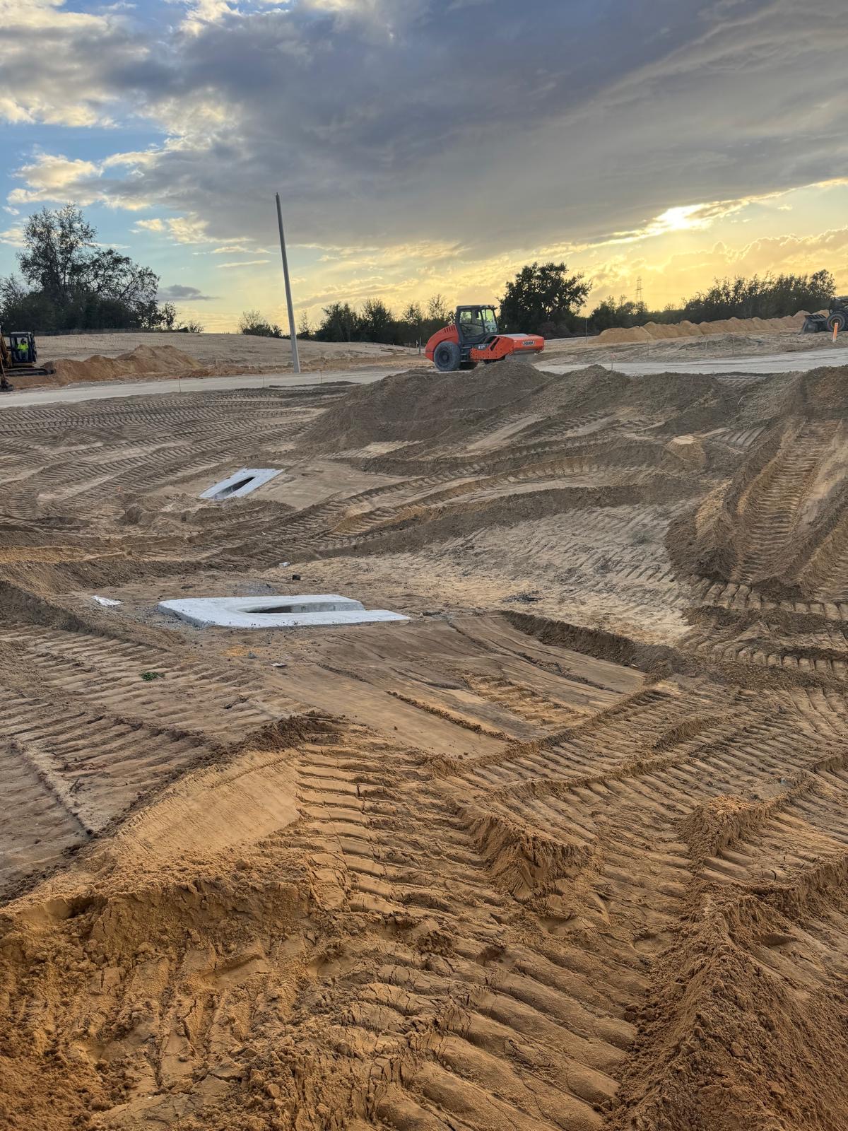 Finish grading work at sunset with roller in the distance